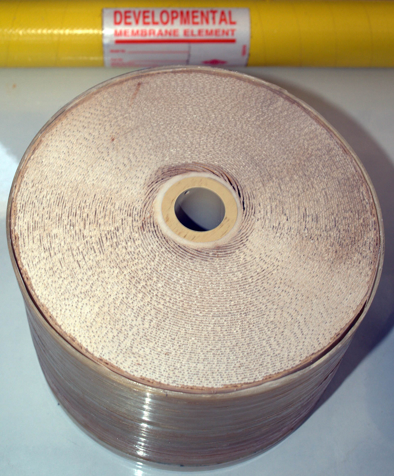A cut spiral-wound reverse-osmosis membrane element: a thick roll of layered sheet around a central tube.